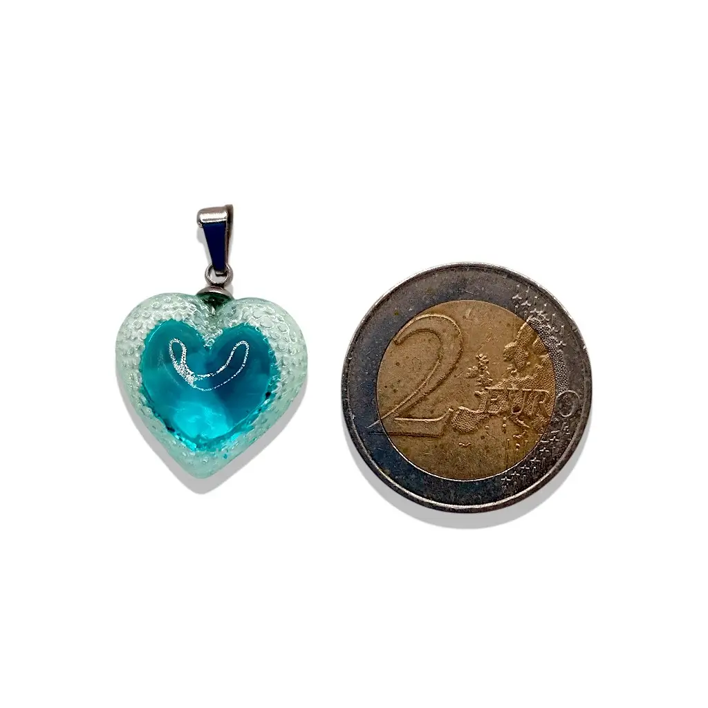 Pendentif cœur Voronoï bleu en résine présenté à côté d’une pièce de 2 euros pour montrer la taille du bijou