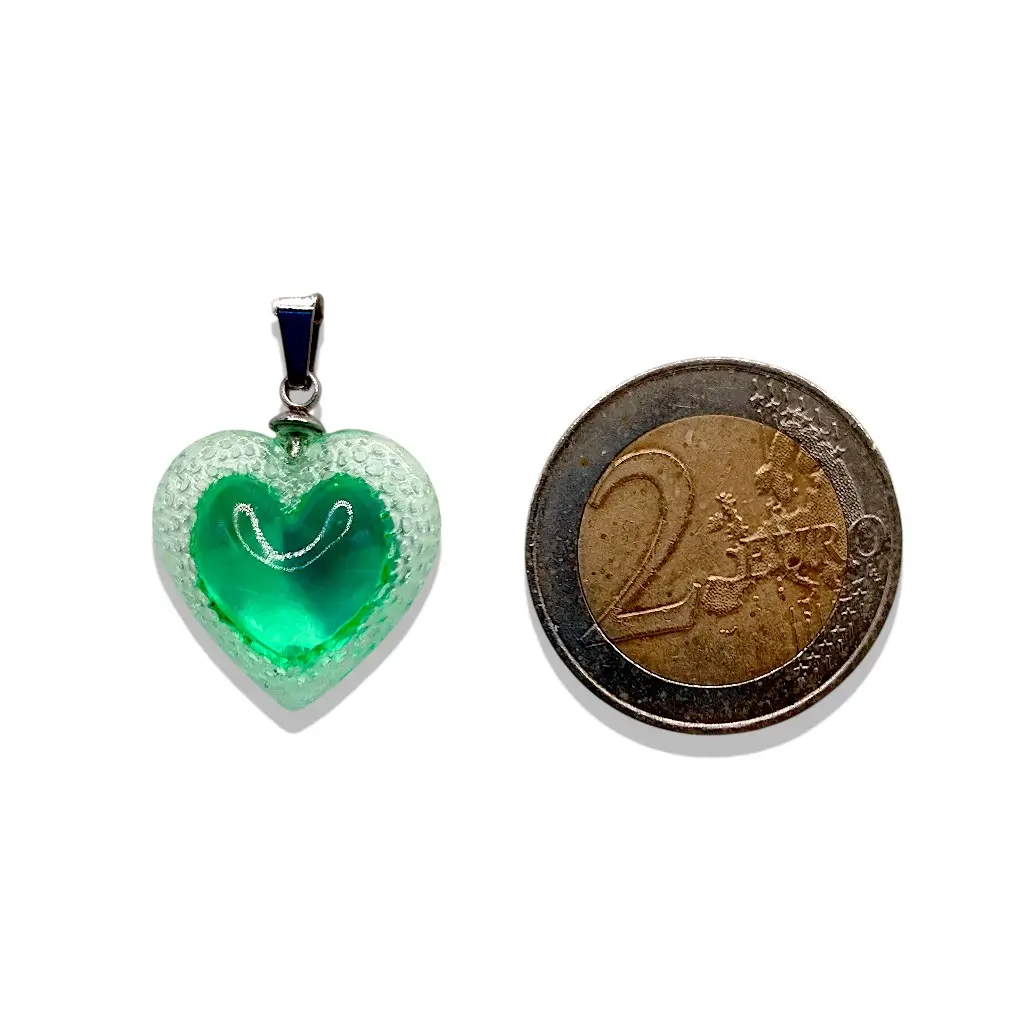Pendentif cœur Voronoï vert en résine présenté à côté d’une pièce de 2 euros pour montrer la taille du bijou