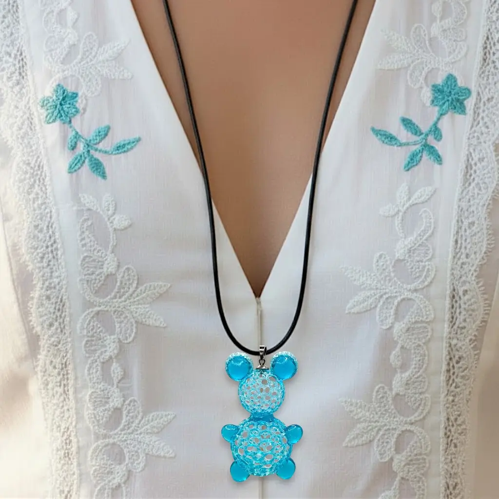 Collier Nounours bleu/vert en résine imprimée en 3D porté sur lien coton ciré noir, avec nœud coulissant, montrant le tombé du bijou
