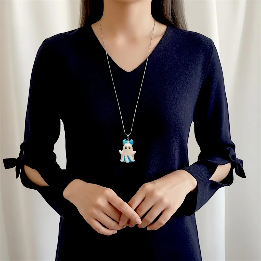 Collier Fantômette bleue porté par une femme, pendentif en résine pailletée avec yeux phosphorescents sur chaîne 50 cm