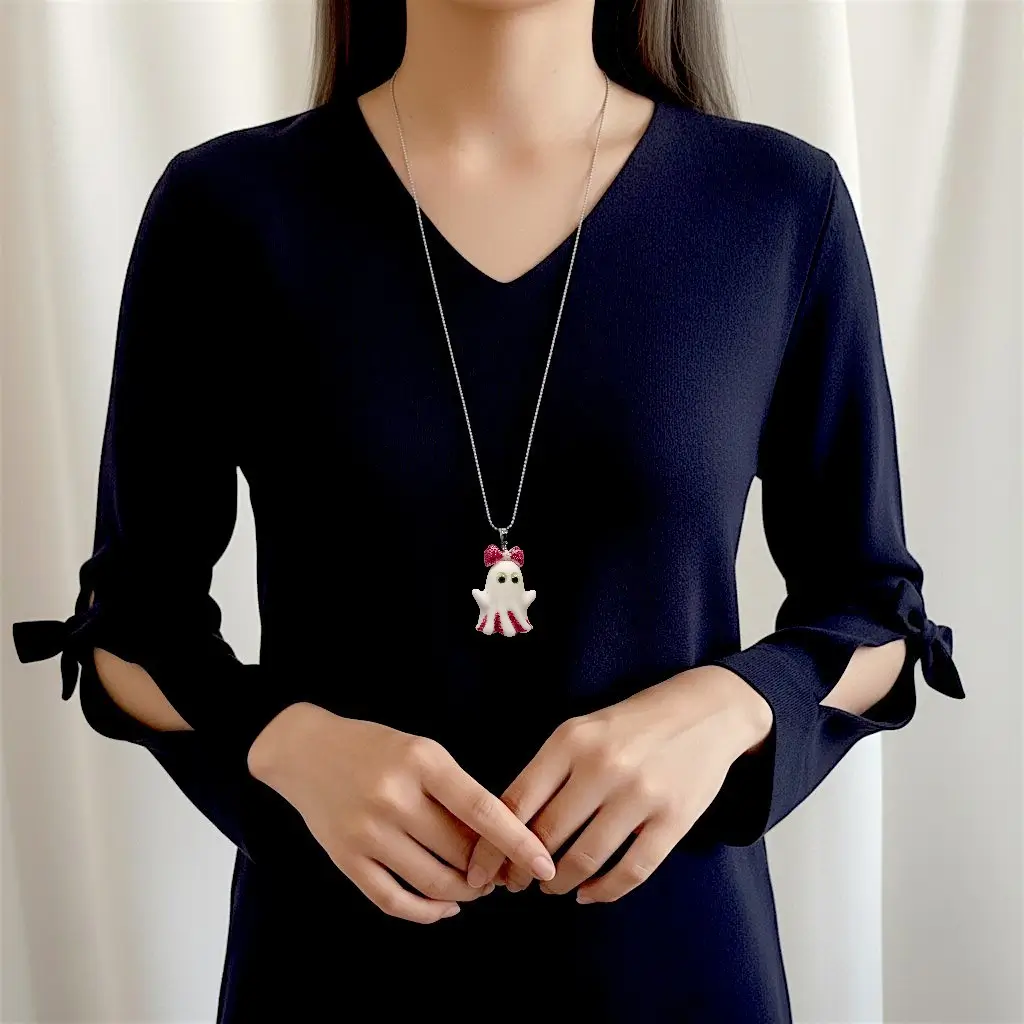 Collier Fantômette framboise porté par une femme, pendentif en résine pailletée avec yeux phosphorescents sur chaîne 50 cm