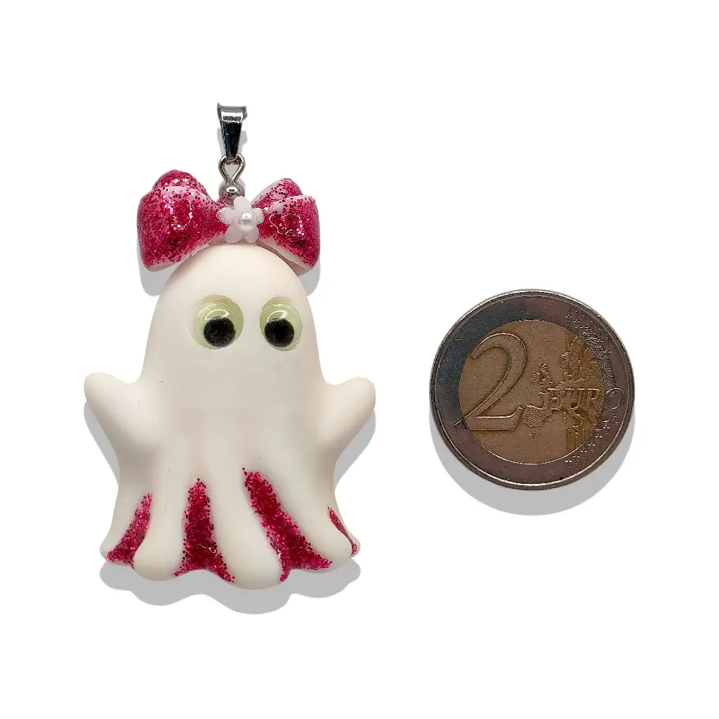 Pendentif Fantômette framboise en résine avec paillettes et yeux phosphorescents à côté d’une pièce de 2 € pour référence taille