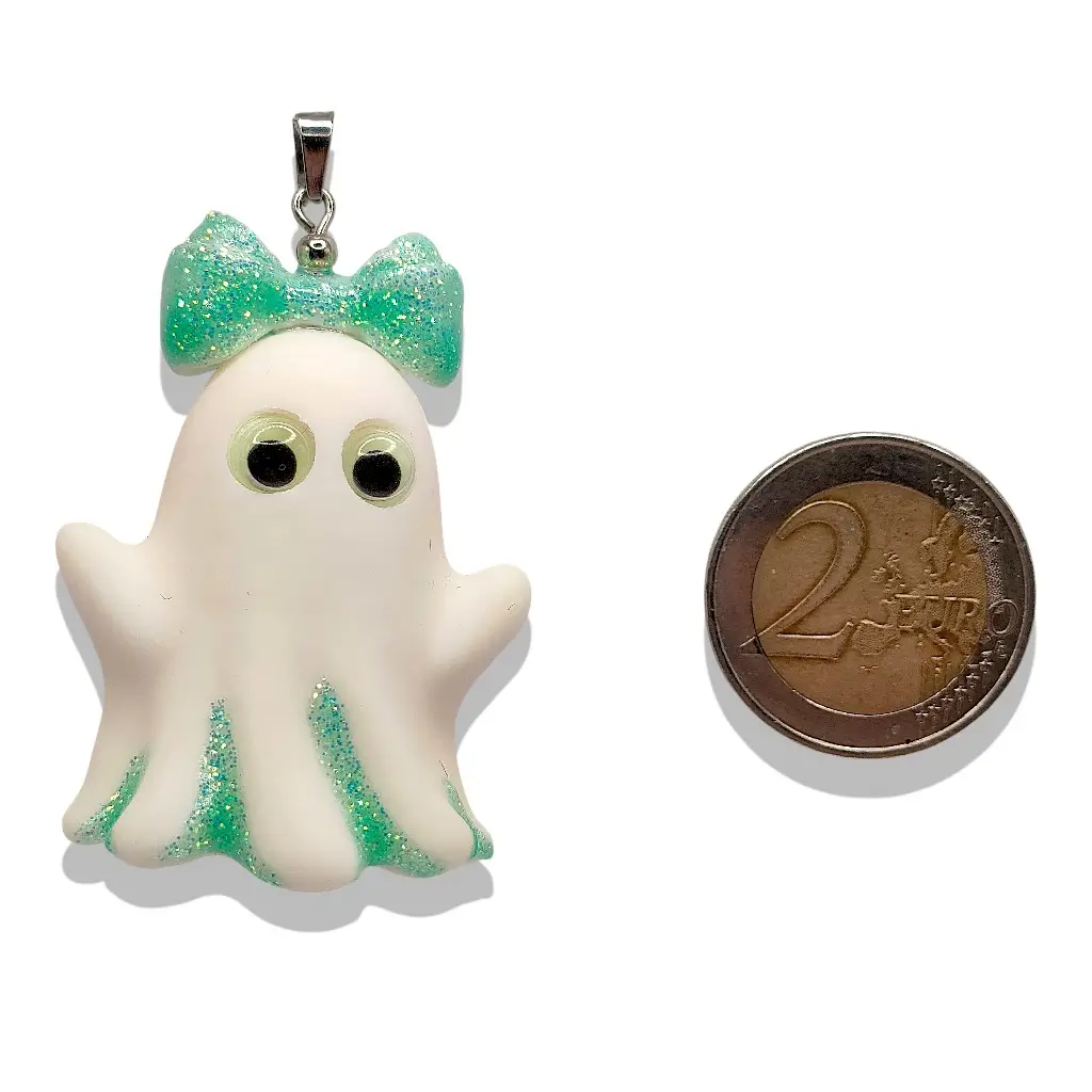Pendentif Fantômette verte en résine avec détails pailletés verts à côté d’une pièce de 2 euros pour référence de taille – Collection P’tit monde