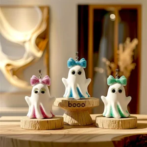 Trois fantômettes en résine imprimées en 3D sur des podiums en bois dont un marqué boo, posées sur une table dans une boutique