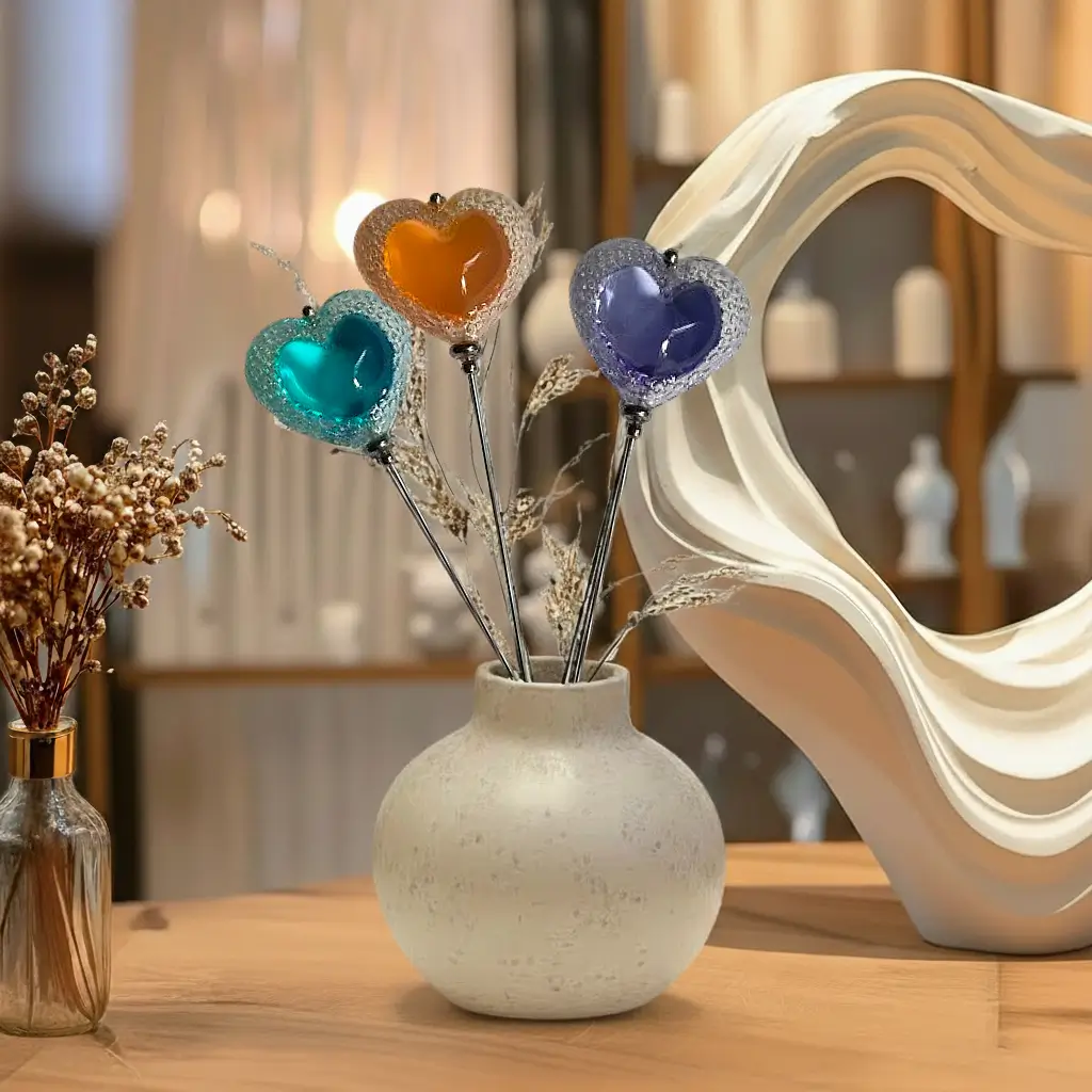 Trois fibules Cœur Voronoï de différentes couleurs en résine imprimée en 3D, présentées dans un vase posé sur une table dans une ambiance de boutique